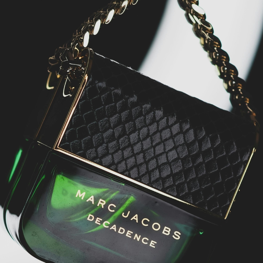 Marc Jacobs Decadence perfume bottle with gold chain handle and black textured cap.