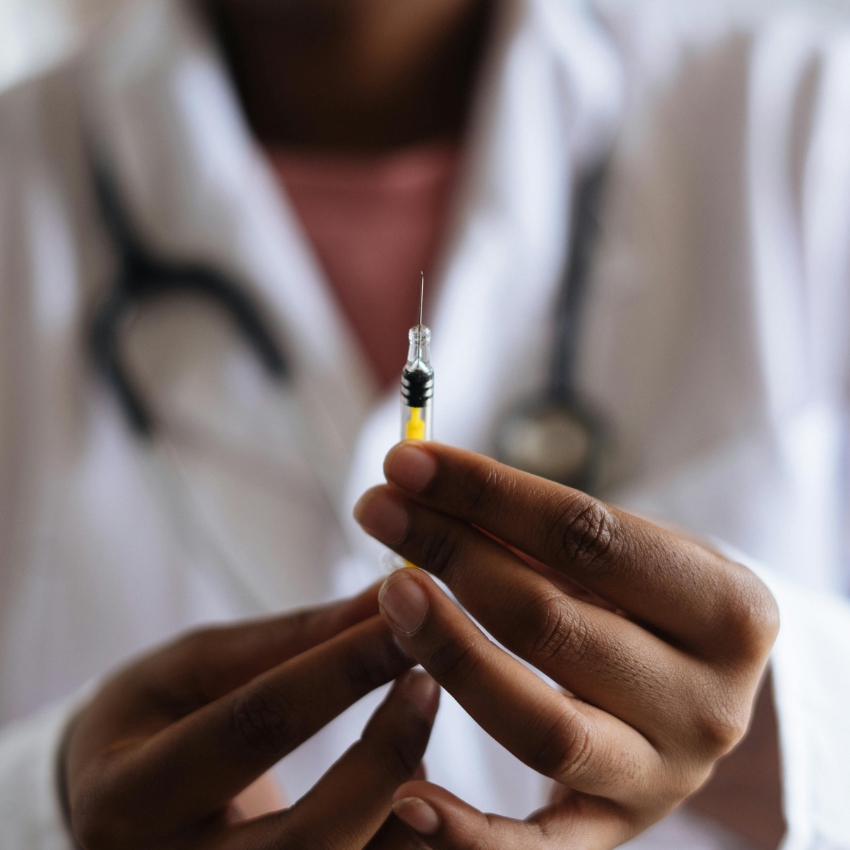 A close-up of hands holding a syringe with a yellow liquid.