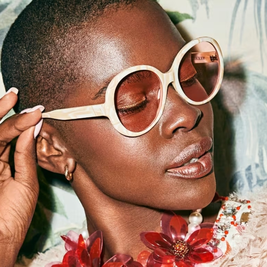 Round-frame sunglasses with cream-colored rims and pink lenses.