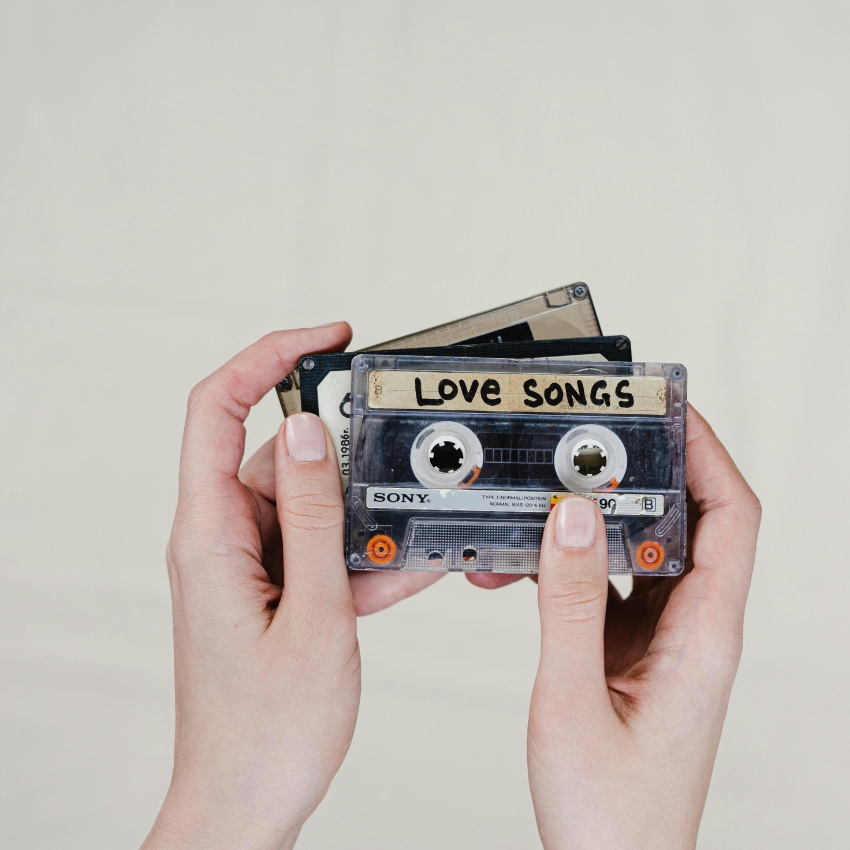 A person holding a cassette tape labeled "Love Songs."