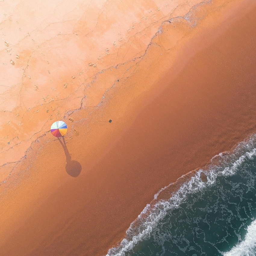 Colorful umbrella on a sandy beach near the ocean.