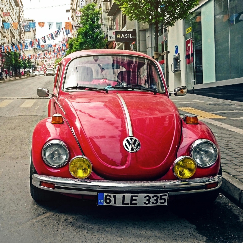 Red Volkswagen Beetle with license plate "61 LE 335" parked on a street.