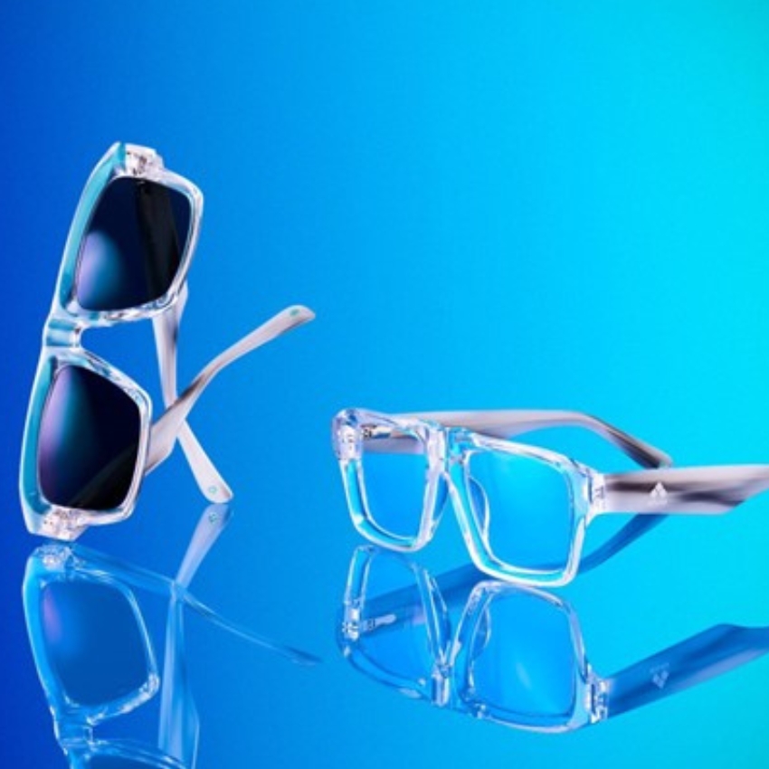 Clear-frame sunglasses with dark lenses and clear, square prescription glasses on a blue background.