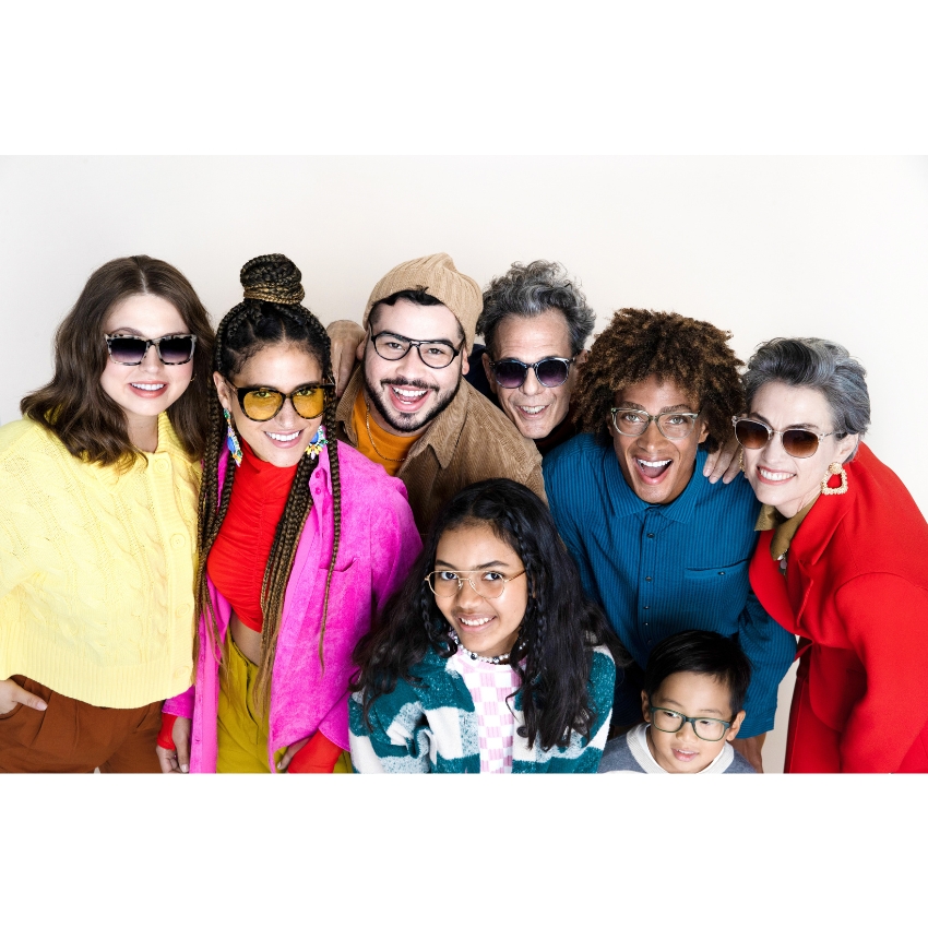 Group of people wearing fashionable, colorful glasses and clothing, smiling and posing together.