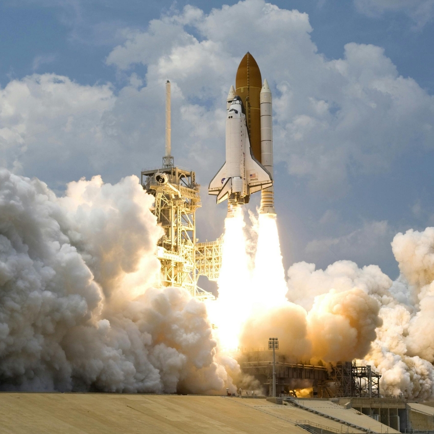 Space shuttle launching with flames and smoke billowing from its engines.