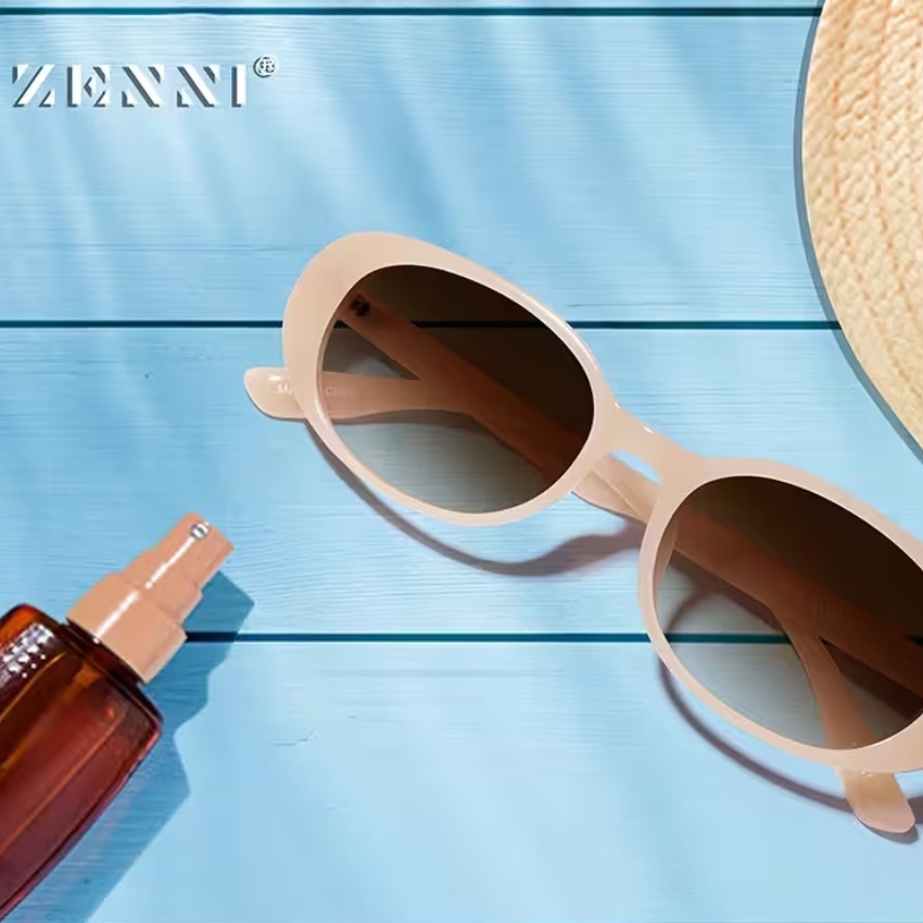 Zenni sunglasses with light pink frames and dark lenses on a blue surface.