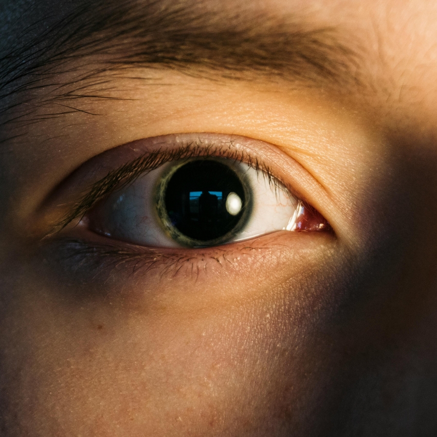 Close-up of a human eye with a dilated pupil reflecting light.