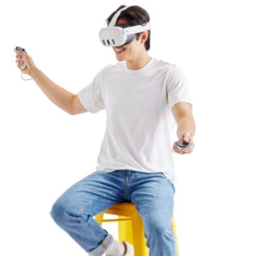 Person sitting on a yellow stool wearing a white VR headset and holding two VR controllers.