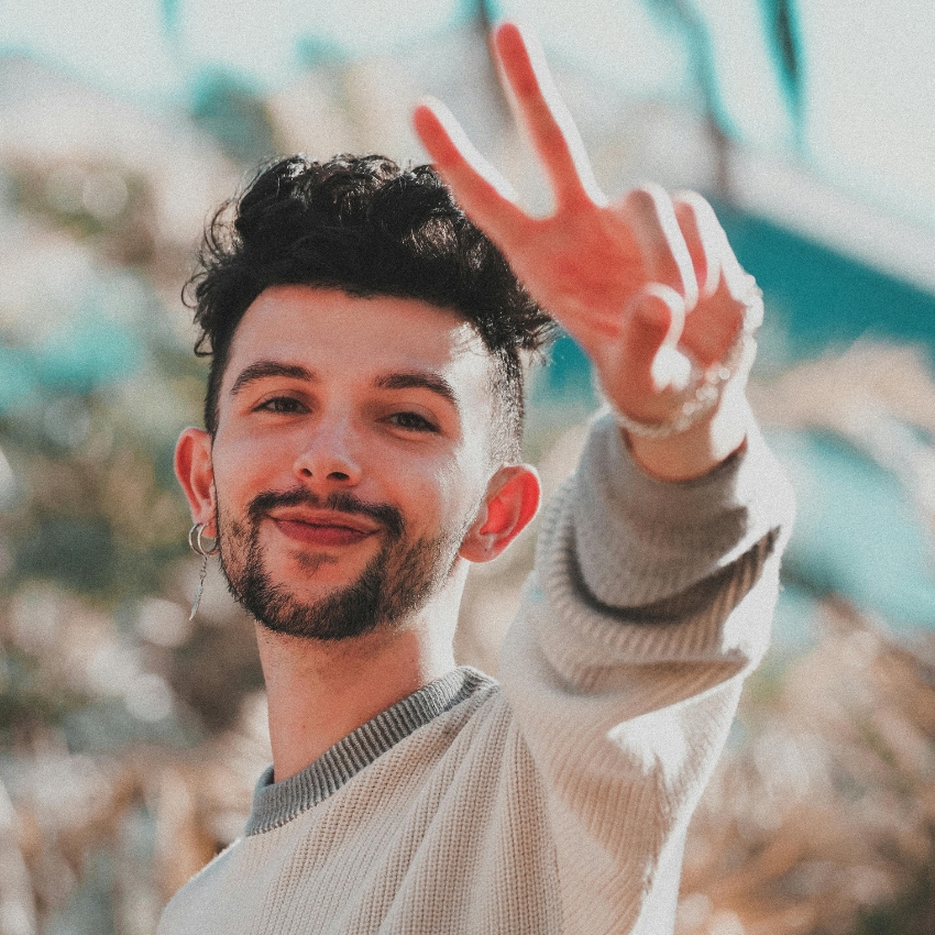 Smiling person giving a peace sign.