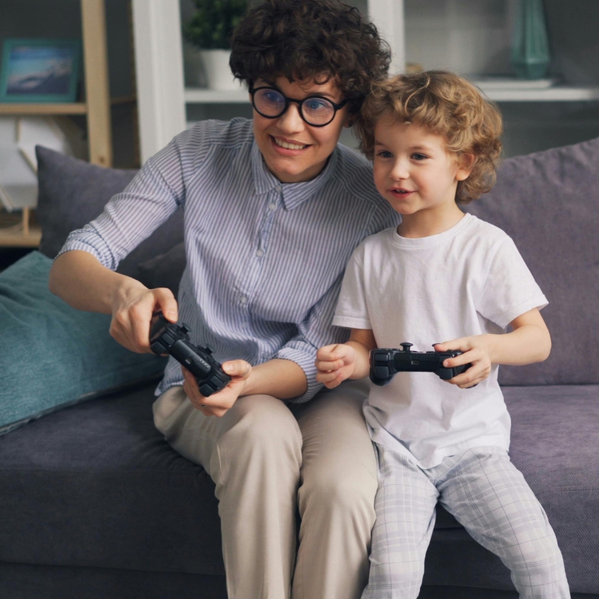 A woman and a child playing a video game with black controllers.