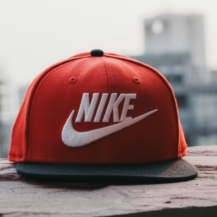 Red Nike cap with white embroidered text "NIKE" and a white swoosh logo, black brim.