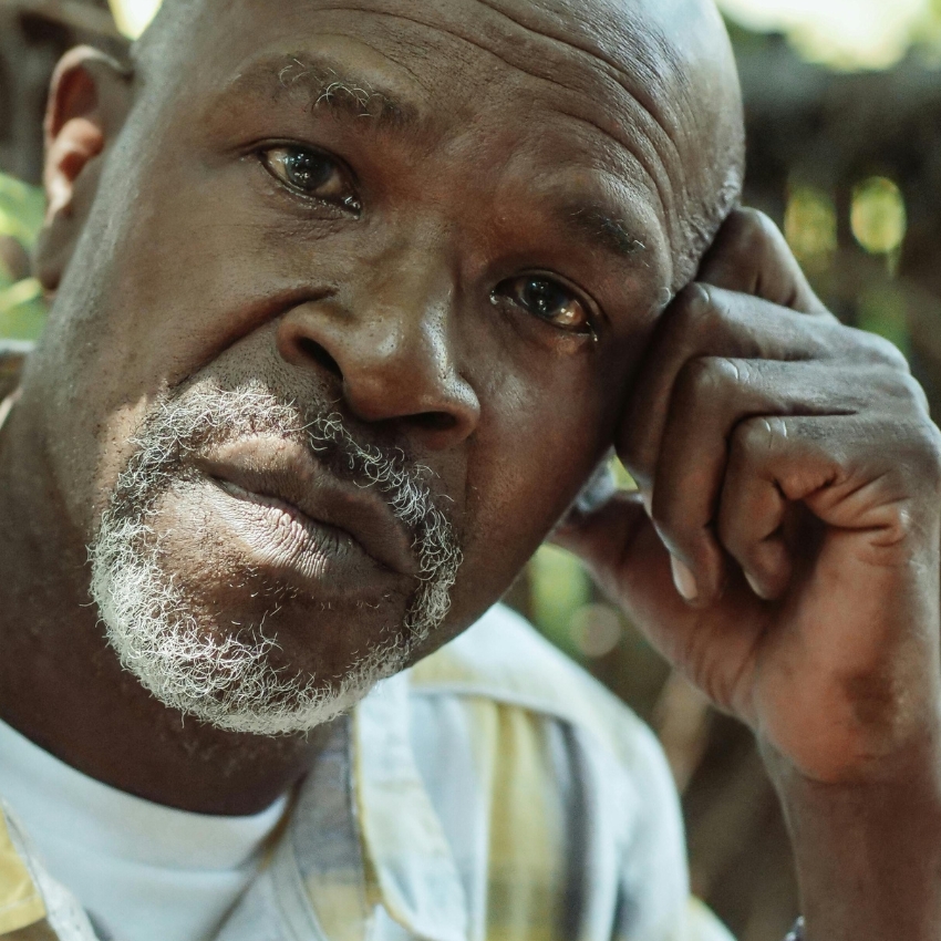 Man with a thoughtful expression, resting his head on his hand.