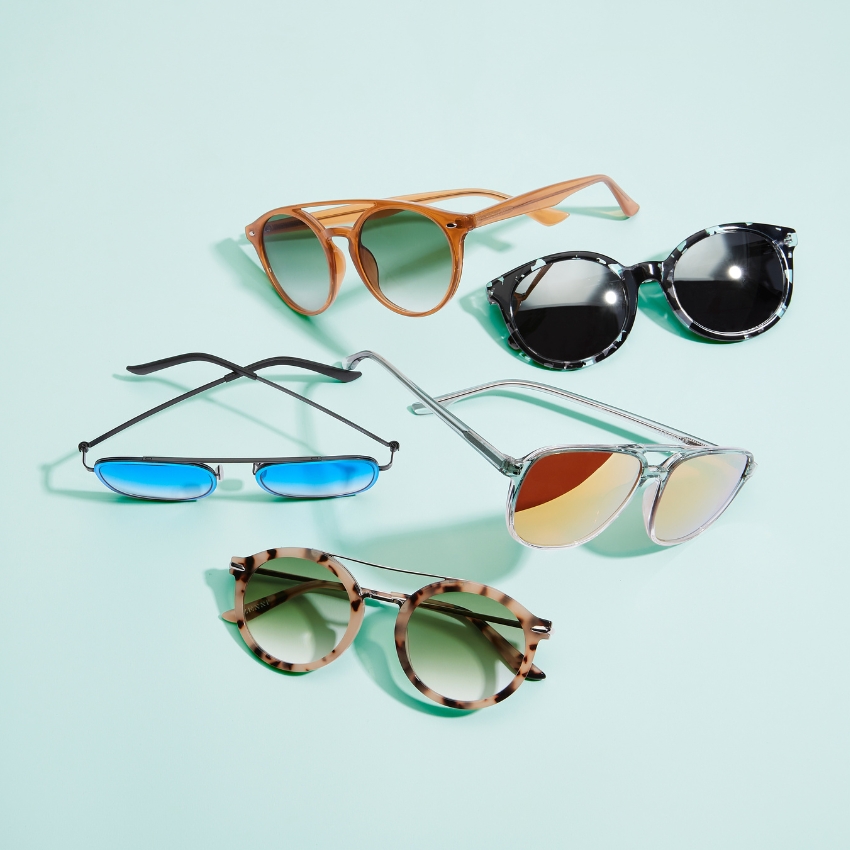 Various styles of sunglasses, including round brown, black and white, blue lens, and mirrored aviator frames.