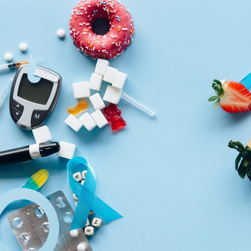 Diabetes-related items: glucometer, insulin pen, sugar cubes, pills, blister pack, syringe, and a blue ribbon.