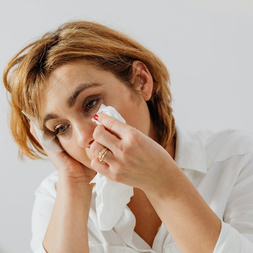 Woman using a tissue to wipe her eye.