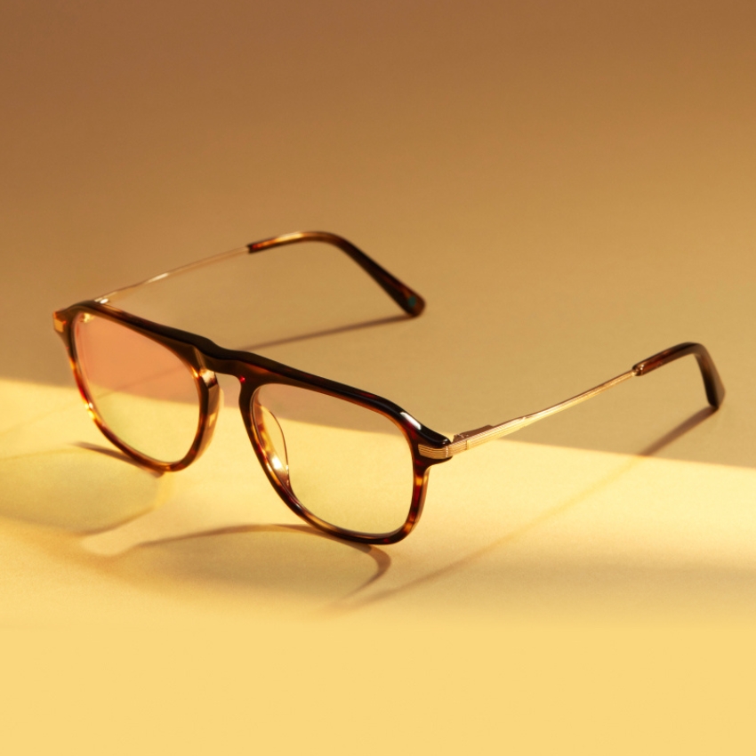 Tortoiseshell square eyeglasses with thin metal arms on a warm-toned background.