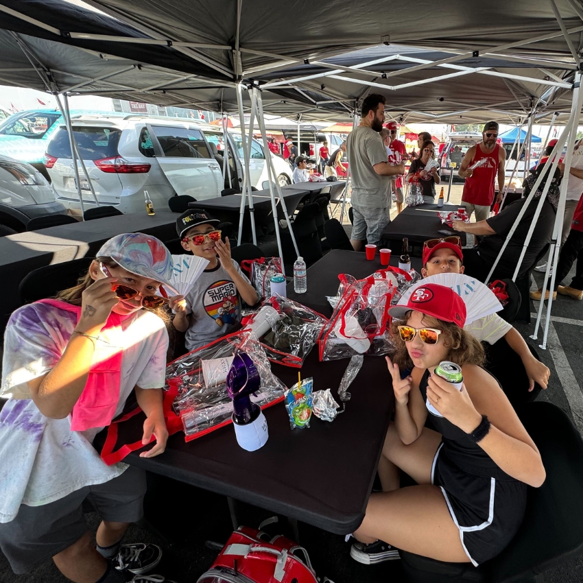 Kids in sports gear with clear backpacks and drinks at a table.