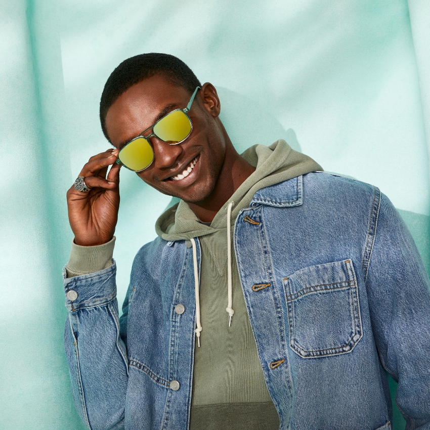 Reflective yellow sunglasses worn by a person in a denim jacket and hoodie.