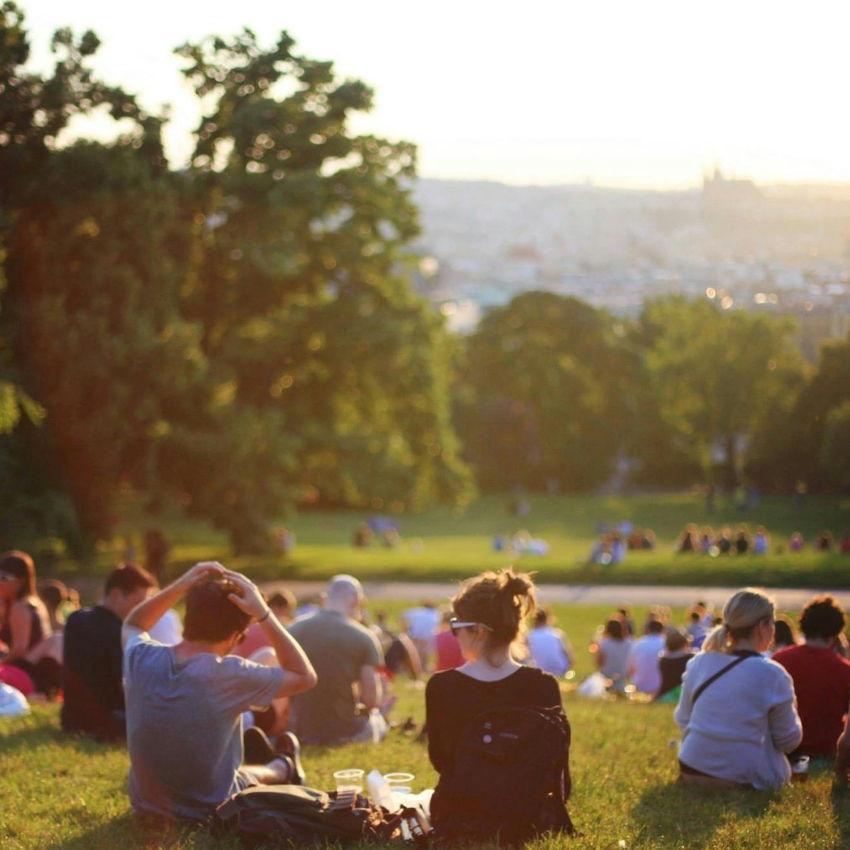 People sitting on a grassy hill during sunset, enjoying the view.