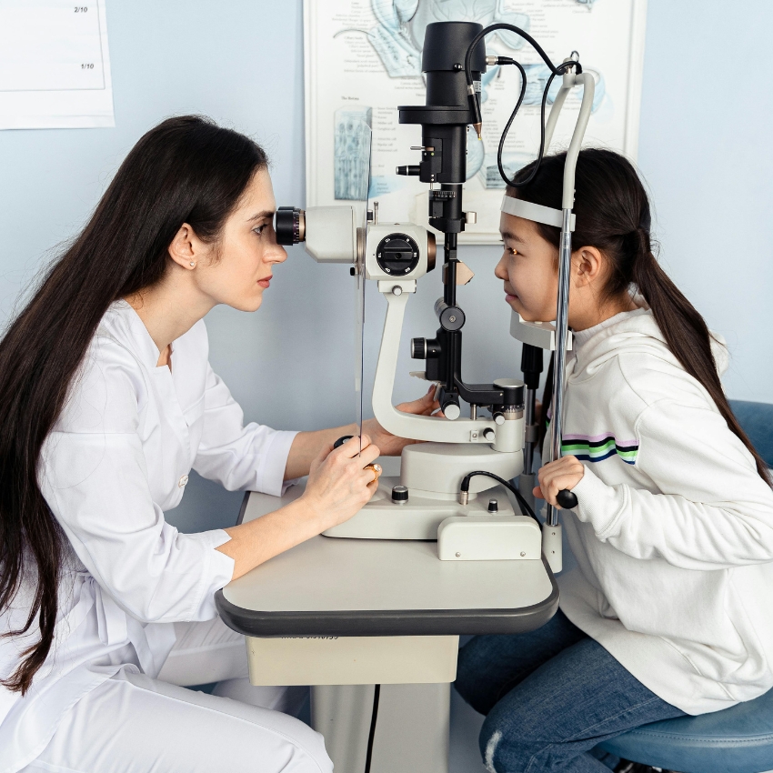 Optometrist using a slit lamp to examine a child's eye.