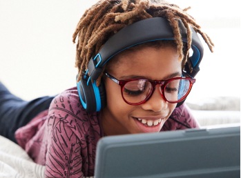 Image of a pre-teen wearing stereo headphones, looking at a computer screen, wearing Zenni glasses.