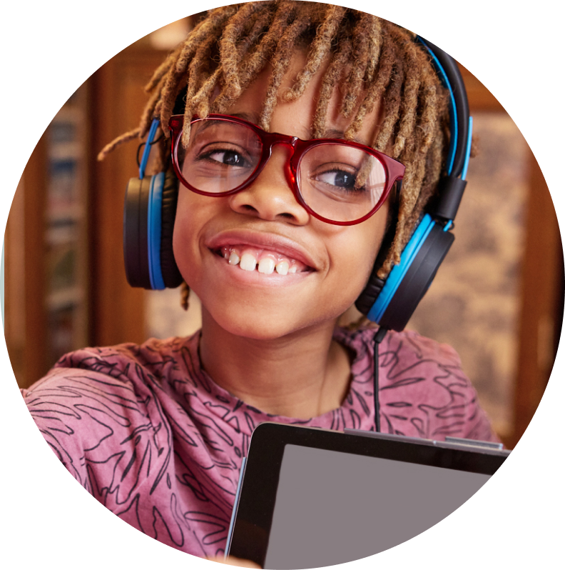 Image of a child wearing zenni glasses, wearing headphones and holding a tablet.